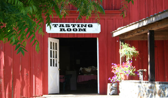 Red barn structure with Tasting Room signage, white doors opened.
