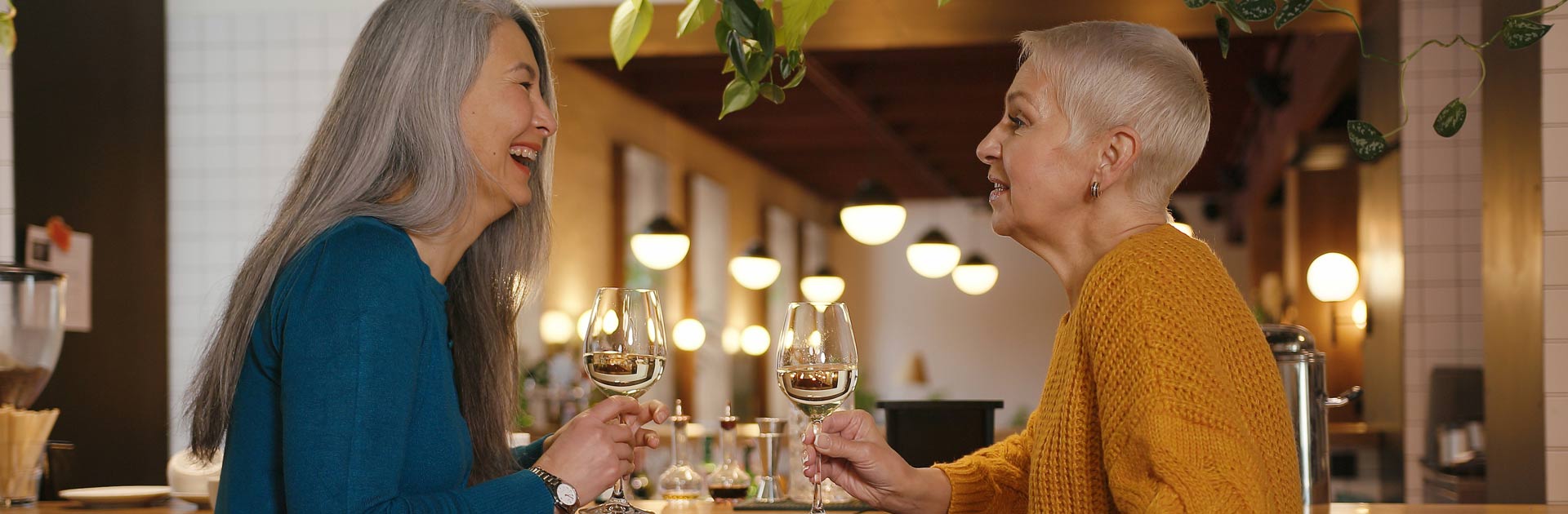 Two women laughing and enjoying a glass of wine in a tasting room.
