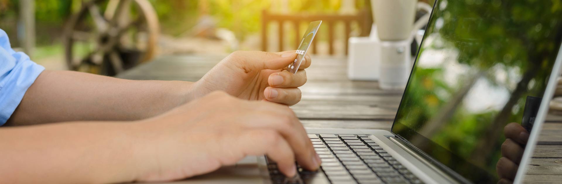 Person at a laptop computer hitting keys and holding a gift card.