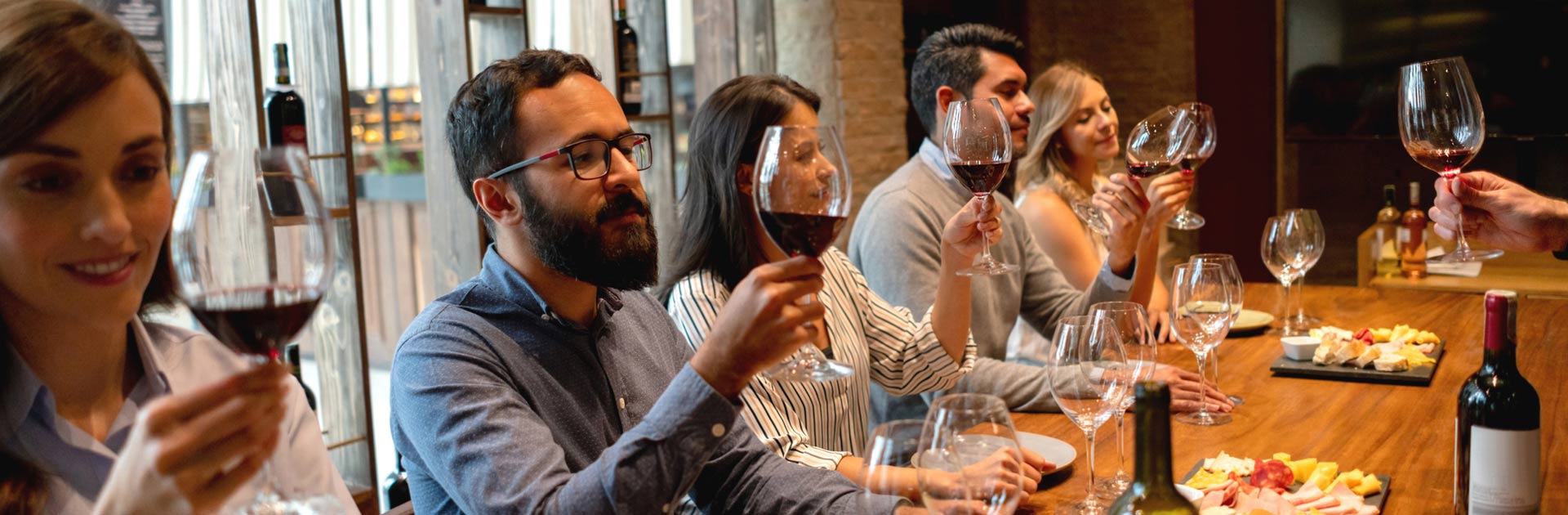 Wine Club members at a wine tasting room discussing a red wine.